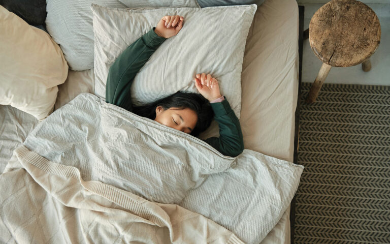 Woman sleeping peacefully in bed, restful sleep and natural sleep supplements.