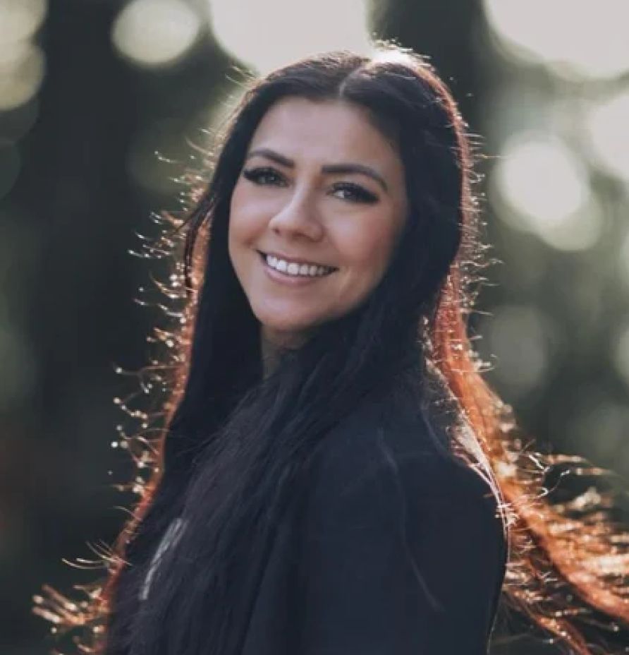 Dr. Tiffany Garcia, smiling with long dark hair, in a natural outdoor setting, representing expertise in nutrition and wellness.