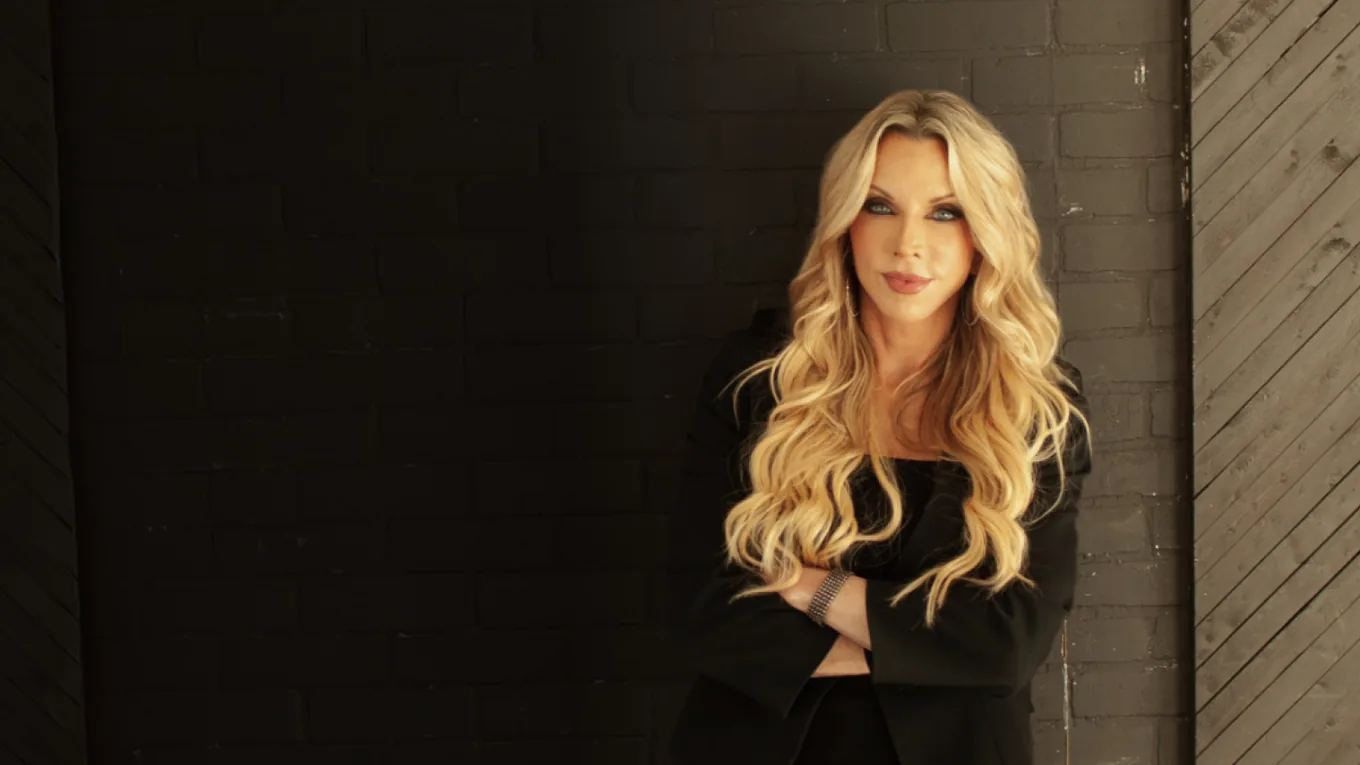 Dr. Amie Hornaman standing against a dark brick wall with her arms folded